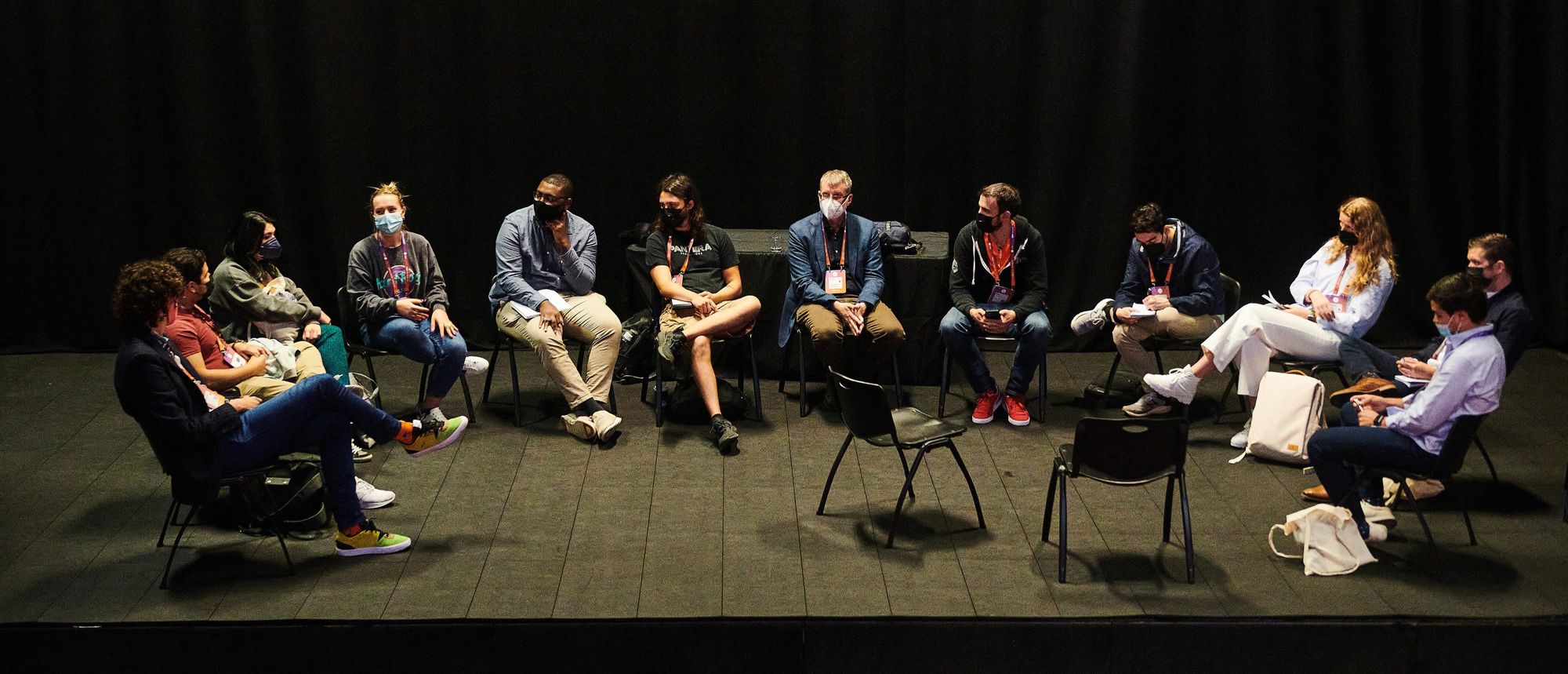 12 people in a semi-circle chatting about a topic during a forum at UXDX USA